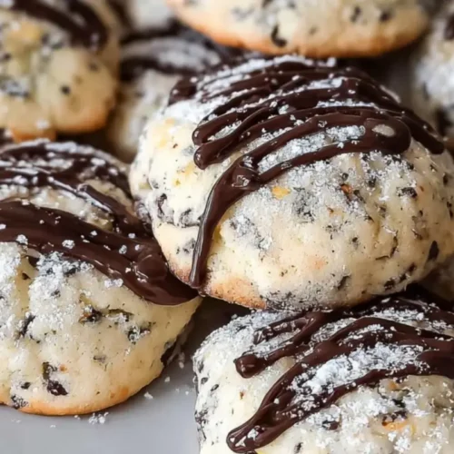 Cannoli Cookies Recipe: The "Bakery-Style" Holiday Favorite (Without the Fryer) Cannoli Cookies Recipe A close-up of soft Italian cannoli cookies drizzled with melted chocolate and dusted with powdered sugar, highlighting their ricotta texture and mini chocolate chips for this cannoli cookies recipe.
