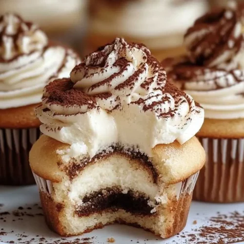 Foolproof Tiramisu Cupcakes (A Heartwarming Italian Showstopper) Tiramisu Cupcakes A batch of homemade tiramisu cupcakes topped with swirls of mascarpone frosting and a light dusting of cocoa powder, arranged on a rustic wooden table in warm natural light.