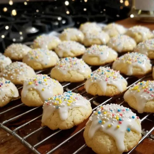 Nonna's Soft Italian Lemon Drop Cookies (Melt In Your Mouth) Italian Lemon Drop Cookies A plate of Authentic Italian Lemon Cookies, soft and golden, with a light dusting of powdered sugar and a hint of lemon zest, arranged on a rustic wooden table.