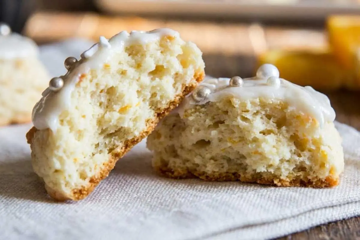 How to Make Italian Orange Ricotta Cookies A close-up view showing the soft, cake-like interior of a glazed treat broken in half on a light linen napkin, illustrating the perfect fluffy texture you achieve when learning how to make Italian orange ricotta cookies.