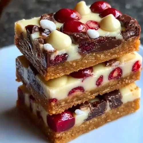 Mom’s Magical Cranberry Cookie Bars (A Foolproof Holiday Showstopper) Cranberry Cookie Bars A vertical stack of three thick cranberry cookie bars loaded with white chocolate chips and tart red cranberries on a white plate.