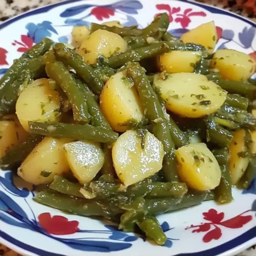 Authentic Italian Green Beans and Potatoes: Nonna’s "No-Mush" Family Heirloom green beans and potatoes A close-up of a comforting side dish of green beans and potatoes tossed in a vibrant, glistening herb dressing, served on a vintage-inspired floral plate.