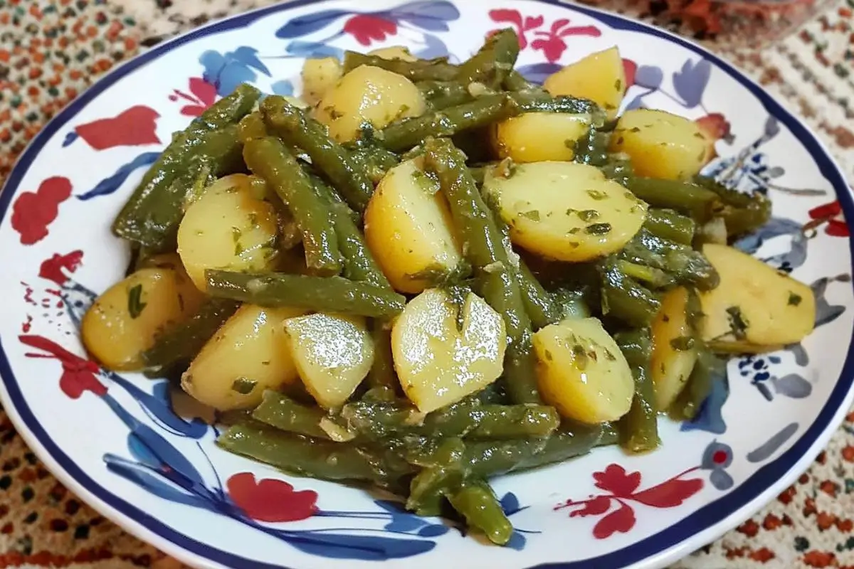 Authentic Italian Green Beans and Potatoes: Nonna’s "No-Mush" Family Heirloom green beans and potatoes A close-up of a comforting side dish of green beans and potatoes tossed in a vibrant, glistening herb dressing, served on a vintage-inspired floral plate.