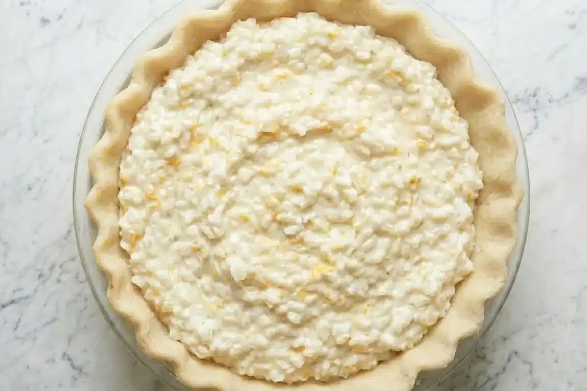 How to Make Italian Rice Pie Step-by-Step An overhead view showing how to make Italian rice pie, featuring a raw, creamy ricotta and rice filling speckled with citrus zest resting inside a fluted pie crust.