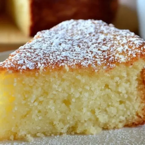 Italian Lemon Ricotta Cake (Nonna's No-Stress Showstopper) Italian Lemon Ricotta Cake A close-up of a tender slice of Italian lemon ricotta cake heavily dusted with powdered sugar on a simple ceramic plate, showing its incredibly moist and fluffy texture.