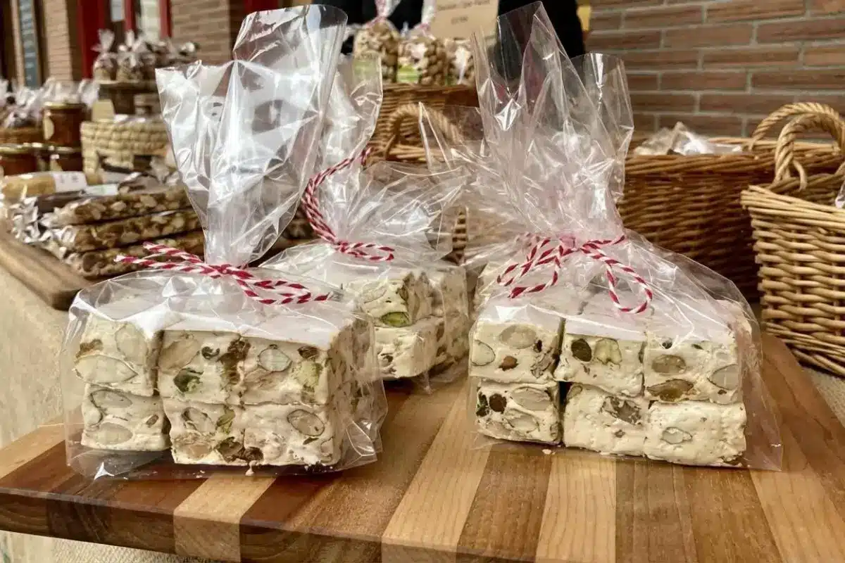 Packaging & Storing Your Classic Italian Torrone Clear cellophane bags filled with thick, nutty squares of classic Italian torrone, beautifully tied with festive red and white baker's twine and resting on a rustic wooden board.
