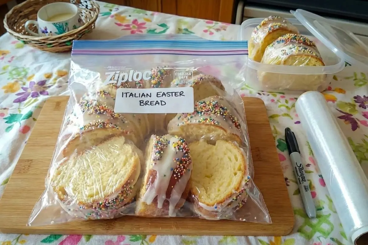 Rena's No-Fail Tips For Your Italian Easter Bread Recipe Individually wrapped slices of glazed Italian Easter bread packed into a labeled clear freezer bag on a wooden cutting board, demonstrating the best method for storing Italian Easter bread.