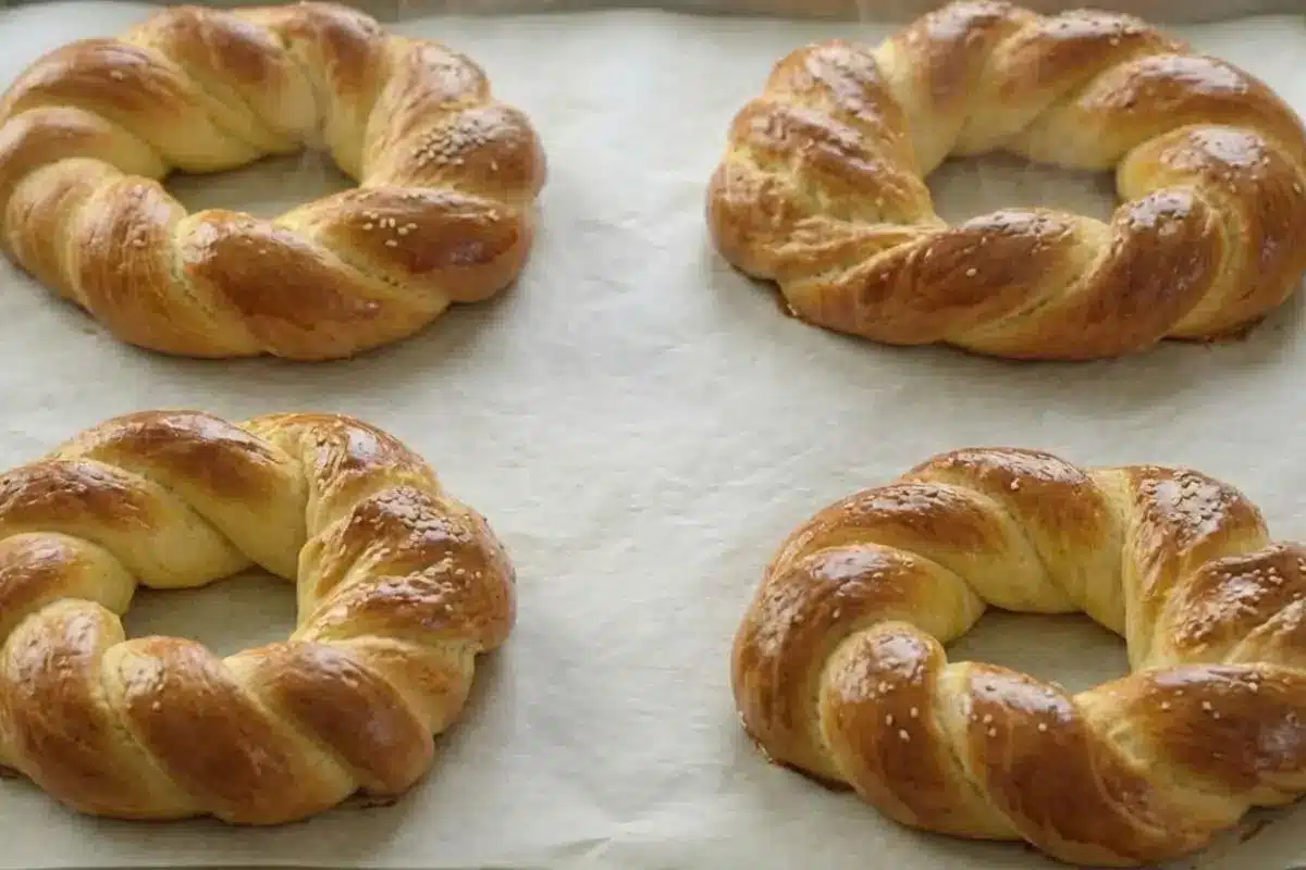Rena's No-Fail Tips For Your Italian Easter Bread Four freshly baked, golden-brown Italian Easter bread rings resting on a parchment-lined baking sheet, fresh from the oven and waiting to cool.