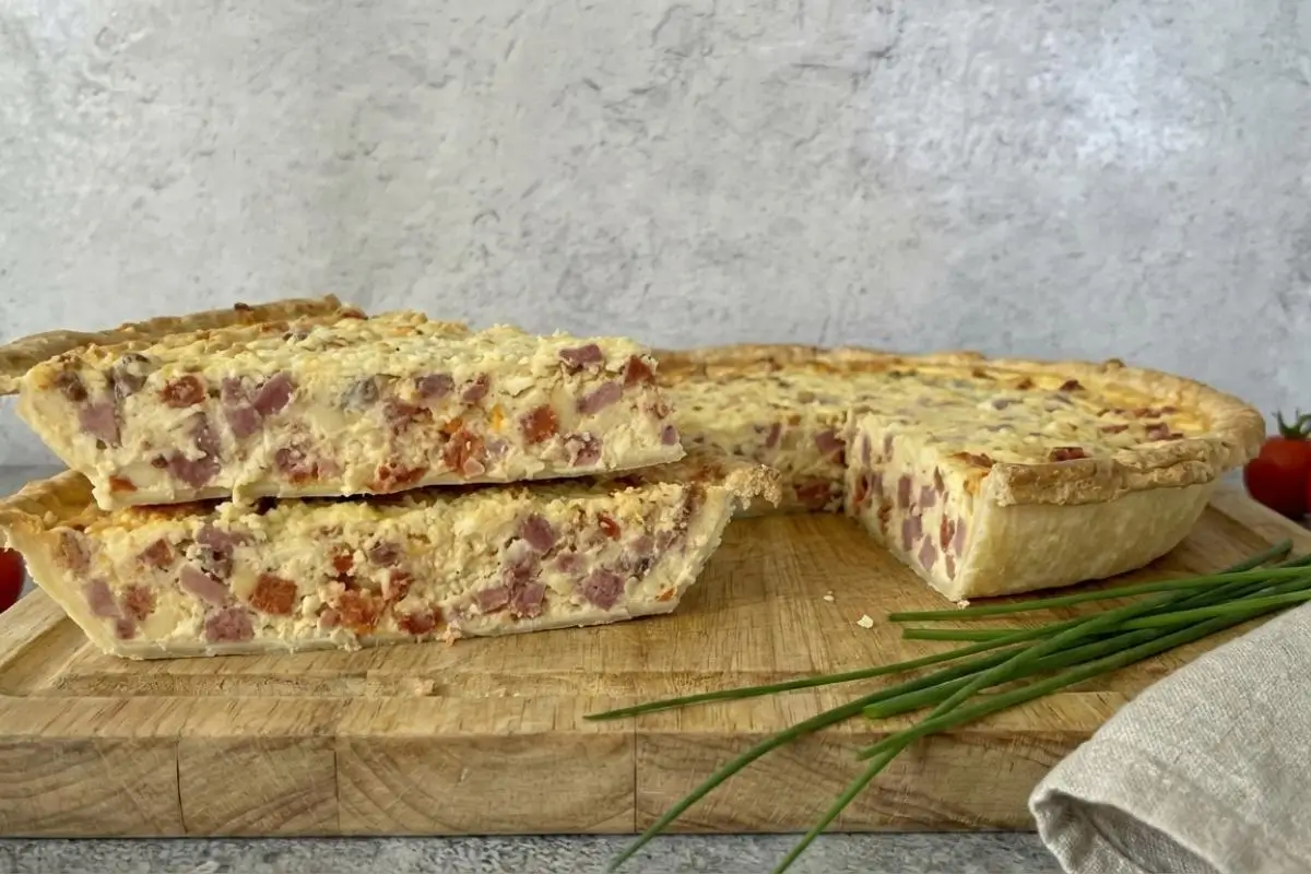 Rena's No-Fail Tips Italian Easter Pie Two thick, hearty slices of savory meat and cheese pie stacked next to the remaining baked tart on a wooden cutting board, perfectly illustrating my no-fail tips for Italian Easter Pie.