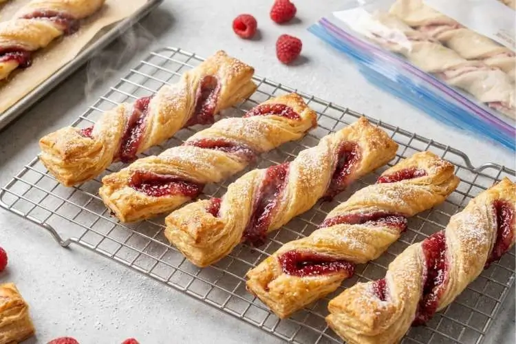 cooling-raspberry-pastry-twists-on-wire-rack Freshly baked Raspberry Pastry Twists cooling on a wire rack, dusted with powdered sugar and filled with sweet raspberry jam.