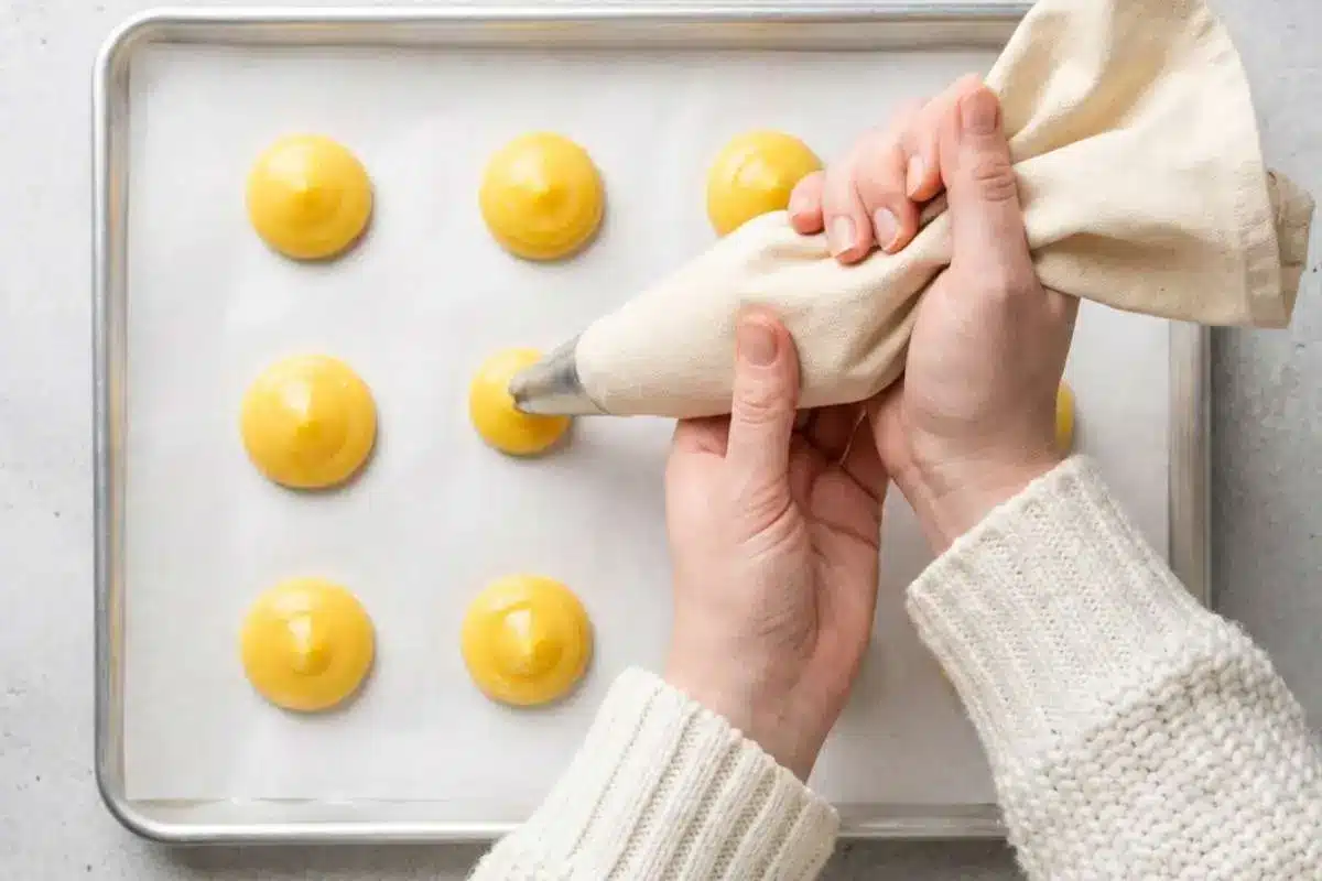 moms-famous-cream-puffs-recipe-piping-choux-pastry Choux pastry dough being piped onto a parchment-lined baking sheet to make Mom’s famous cream puffs recipe.