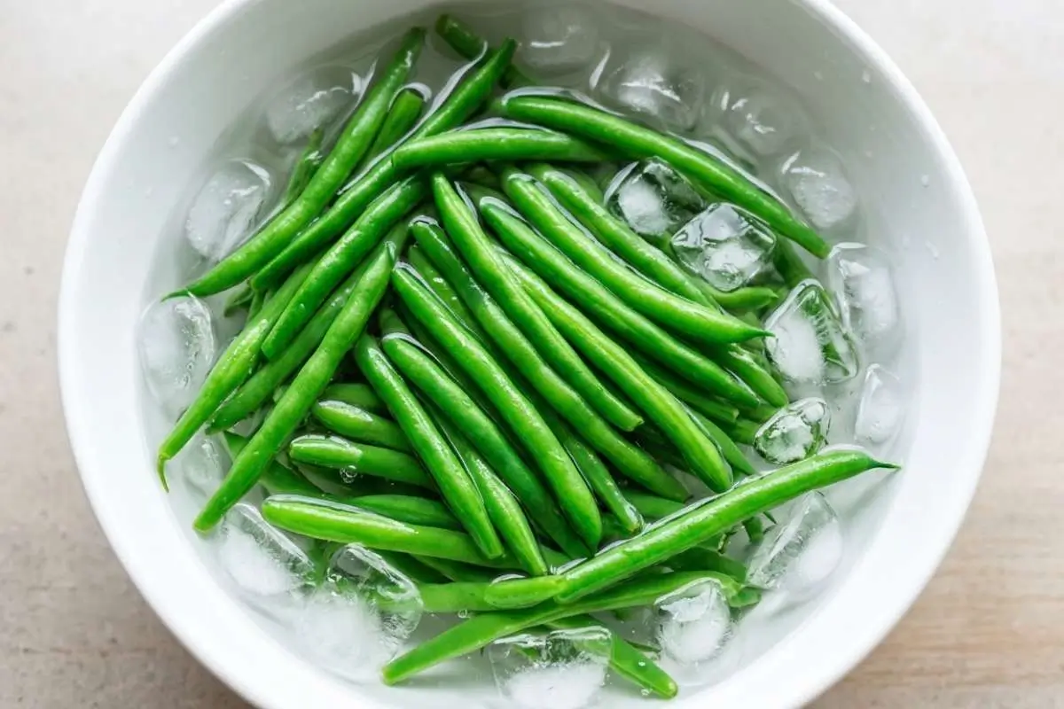 boiled-baby-potatoes-recipe-blanching-green-beans (2) Fresh green beans being added to boiling water while preparing a boiled baby potatoes recipe with vegetables.
