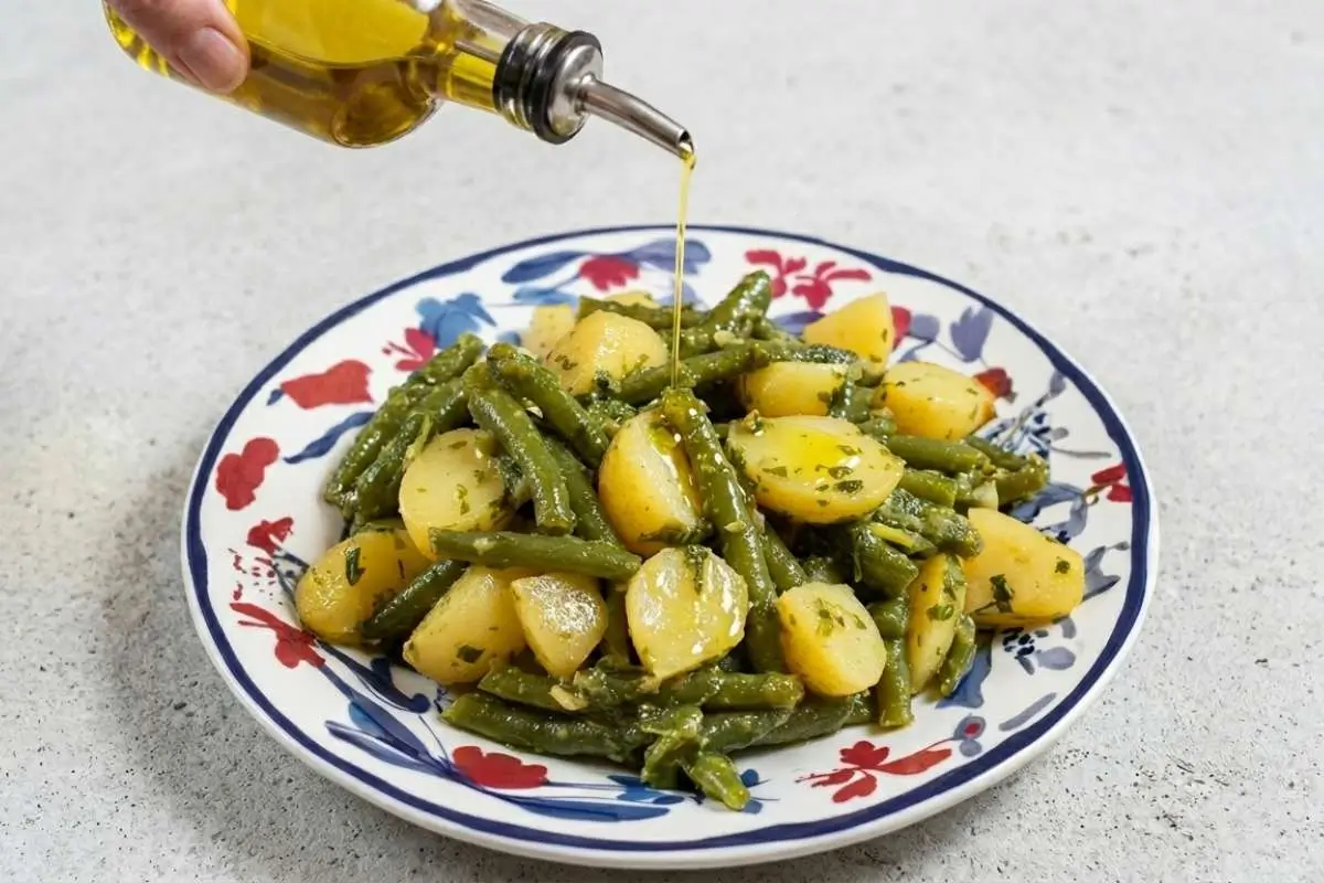 boiled-baby-potatoes-recipe-serving-with-olive-oil Boiled baby potatoes and green beans being drizzled with olive oil on a plate for a boiled baby potatoes recipe.