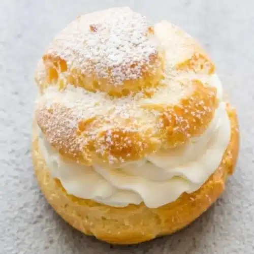 The Most Heavenly Cream Puff Filling Recipe (A 10-Minute Stress-Free Shortcut!) cream puff filling recipe A homemade cream puff filled with rich cream puff filling and dusted with powdered sugar on top.