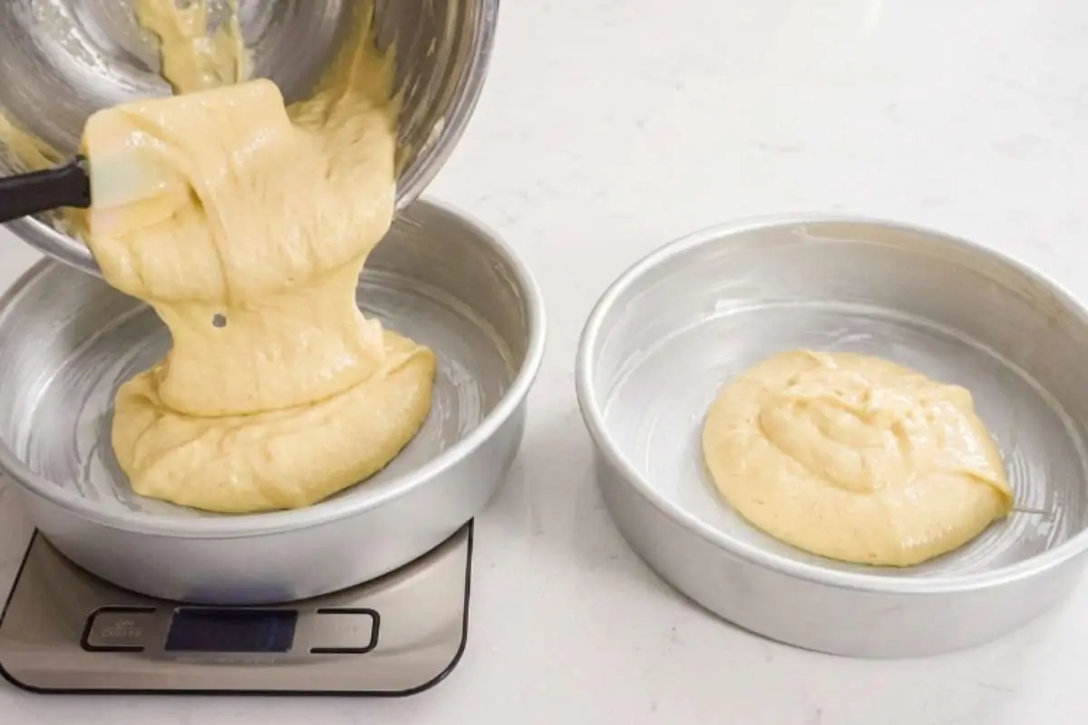 white-chocolate-raspberry-cake-recipe-cake-batter-pans Cake batter being poured evenly into round cake pans for a white chocolate raspberry cake recipe.